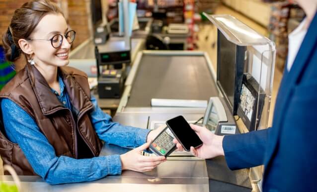 un uomo effettua un pagamento al supermercato utilizzando il suo smartphone