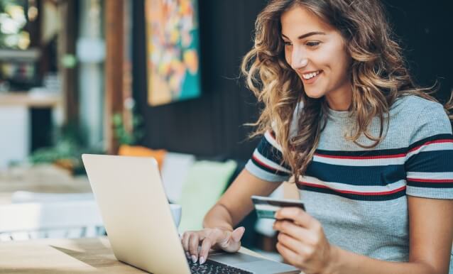 Donna al computer portatile con carta di credito, impegnata in un acquisto o in una transazione online.