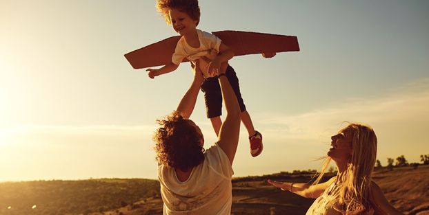 Un uomo e una donna alzano un bambino, esprimendo amore e protezione, simbolo di previdenza.